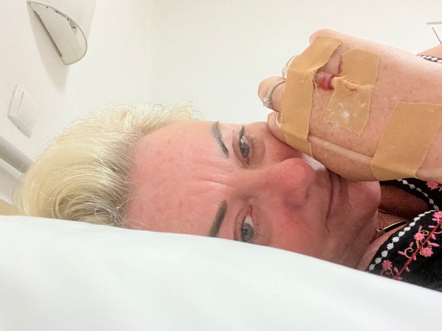 Nicky lying on a hospital bed with a cannula in her hand